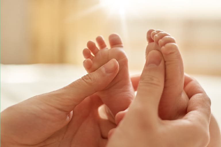 benefits of prenatal vitamins helps your baby grow stronger - Picture of a mother's hand under a baby's feet   