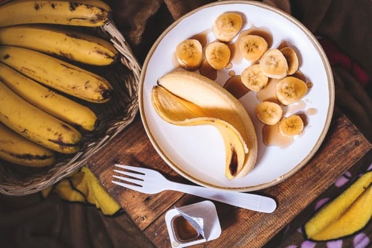 A bowl of bananas with a plate containing banana pieces